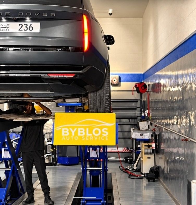 A Range Rover raised on a scissor lift next to the yellow BYBLOS sign